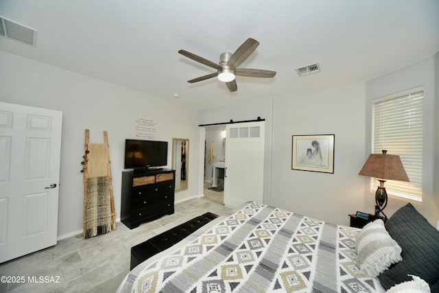 bedroom with connected bathroom, a barn door, and ceiling fan