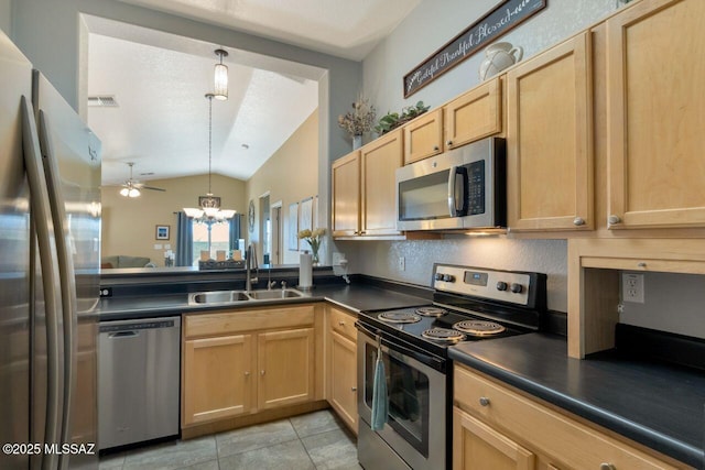 kitchen with appliances with stainless steel finishes, dark countertops, a sink, and decorative light fixtures