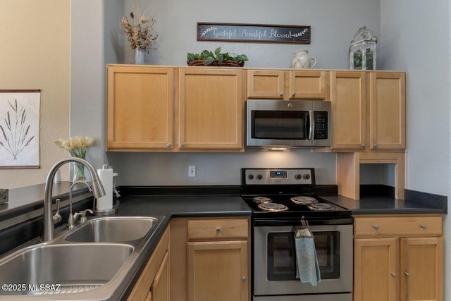 kitchen featuring appliances with stainless steel finishes, dark countertops, light brown cabinets, and a sink