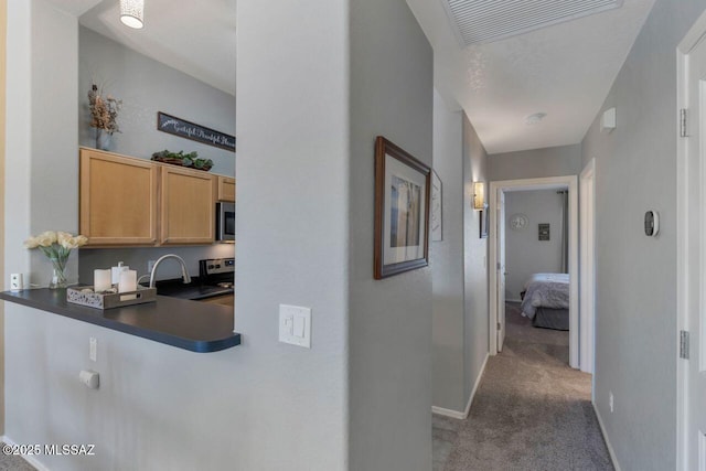 corridor featuring baseboards, visible vents, dark colored carpet, and a sink