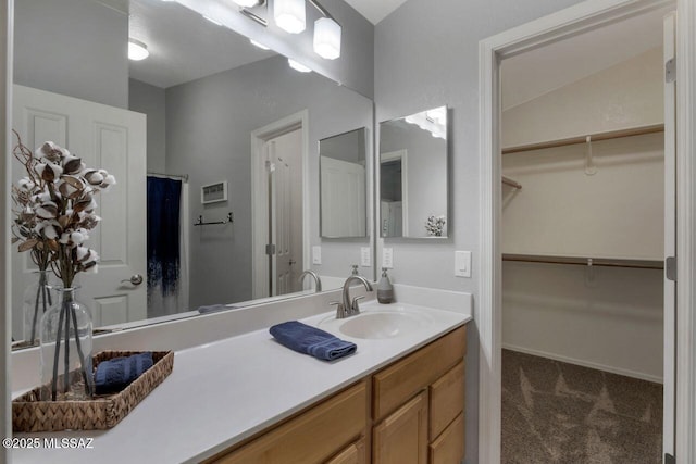 bathroom featuring baseboards, a spacious closet, and vanity