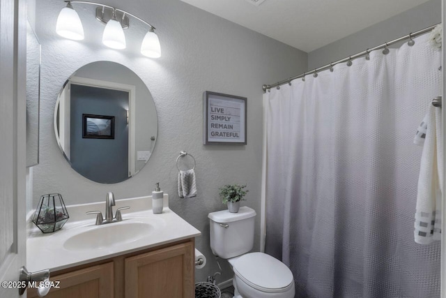 full bath featuring toilet, a textured wall, vanity, and a shower with curtain