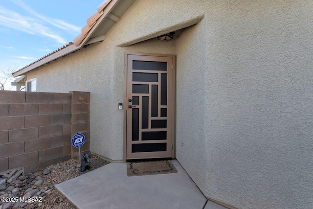 property entrance featuring fence and stucco siding