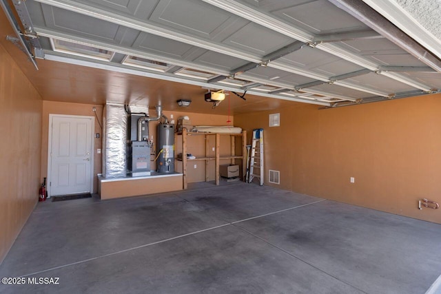 garage featuring a garage door opener, gas water heater, and visible vents