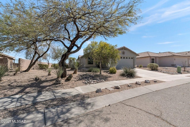 view of front of property with driveway, a garage, a residential view, fence, and stucco siding