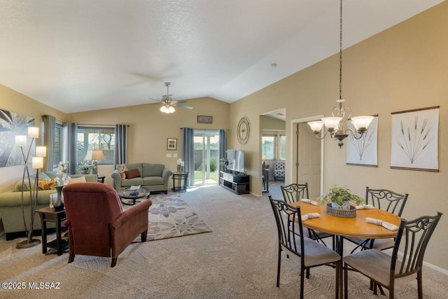 dining space with lofted ceiling, ceiling fan with notable chandelier, baseboards, and light colored carpet