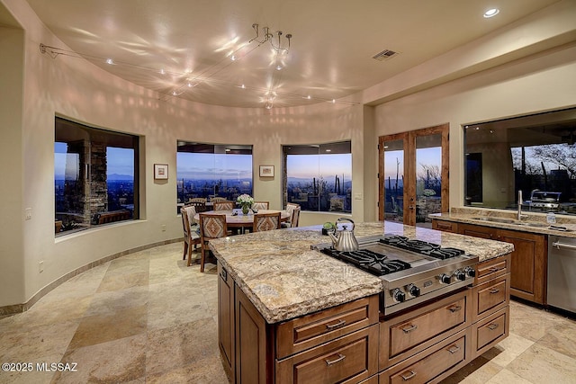 kitchen featuring sink, appliances with stainless steel finishes, a center island, light stone counters, and french doors