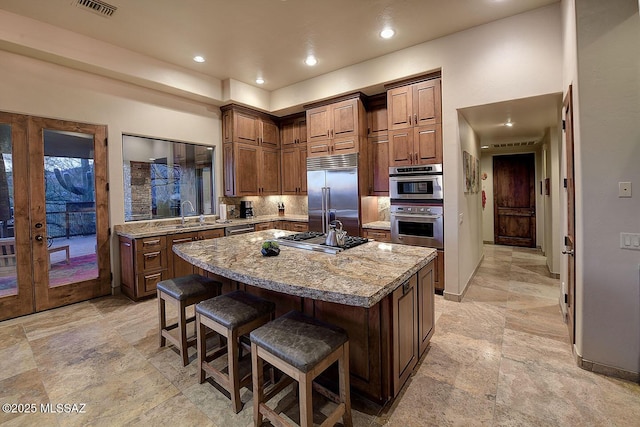 kitchen with a kitchen island, a breakfast bar, sink, stainless steel appliances, and french doors