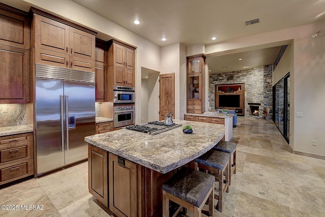 kitchen with light stone counters, appliances with stainless steel finishes, a center island, and a breakfast bar area