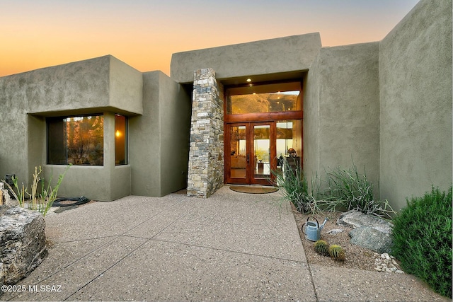 exterior entry at dusk with a patio area and french doors