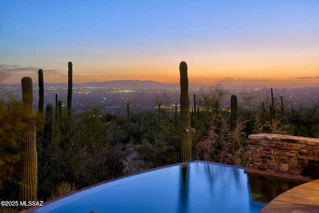 pool at dusk with a water and mountain view