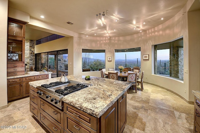 kitchen with stainless steel gas stovetop, a kitchen island, and light stone counters