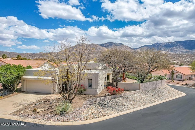 view of front facade with a mountain view, an attached garage, driveway, and stucco siding
