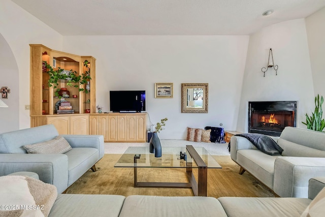 living room with arched walkways and a lit fireplace