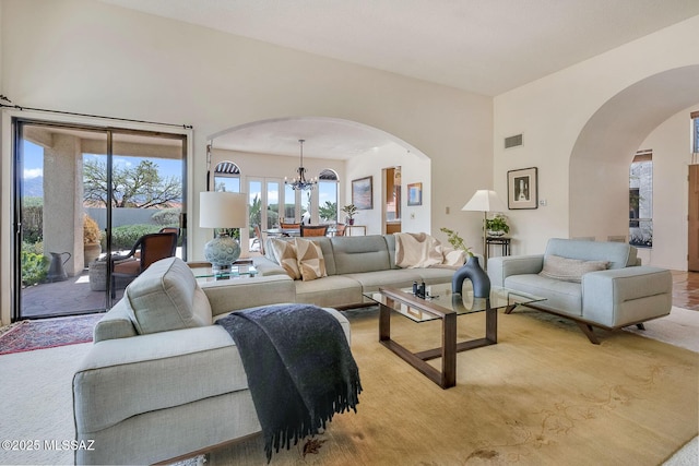 living room featuring arched walkways, an inviting chandelier, light carpet, and visible vents