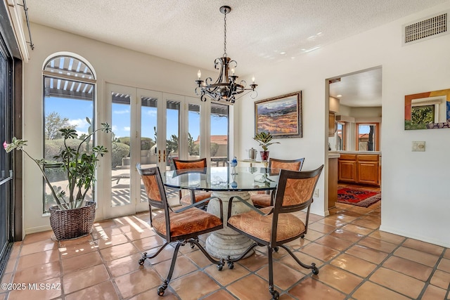 dining room with light tile patterned floors, visible vents, a textured ceiling, and an inviting chandelier