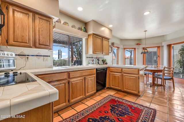 kitchen with a peninsula, tile counters, black appliances, recessed lighting, and decorative backsplash