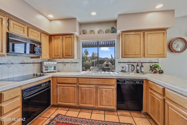 kitchen with a sink, black appliances, backsplash, and light tile patterned flooring