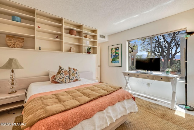 carpeted bedroom featuring a textured ceiling and visible vents