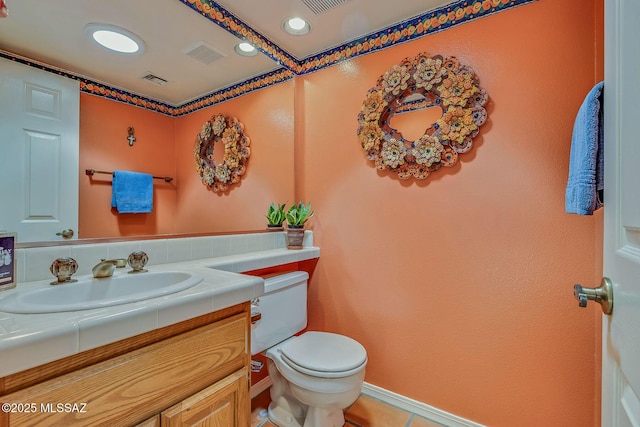 half bathroom featuring tile patterned flooring, vanity, visible vents, and toilet