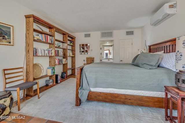 bedroom featuring visible vents, a textured ceiling, and a wall unit AC