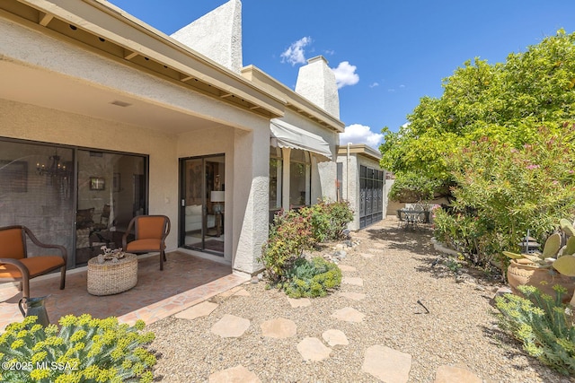 back of property featuring a chimney, a patio area, and stucco siding
