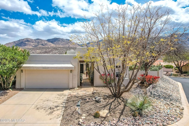 view of front of home featuring concrete driveway, stucco siding, a mountain view, a garage, and fence