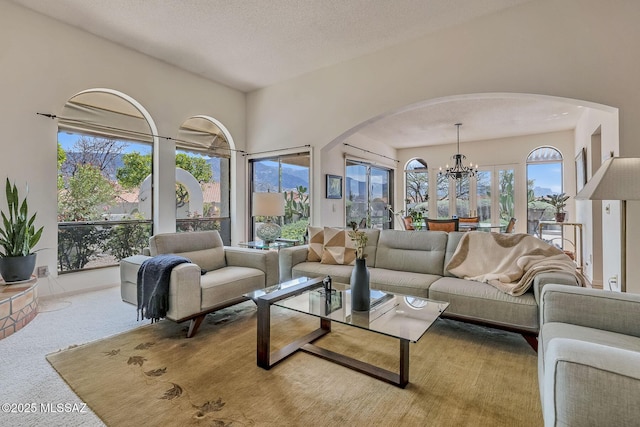living area with arched walkways, an inviting chandelier, and carpet