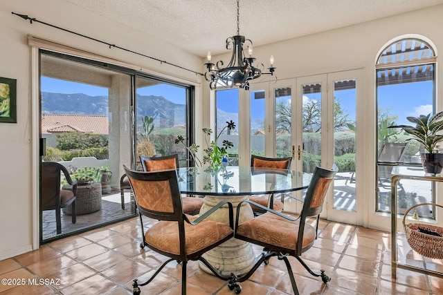 dining space featuring a mountain view, light tile patterned floors, a notable chandelier, and a textured ceiling