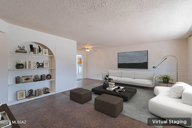 tiled living room with ceiling fan, built in shelves, and a textured ceiling