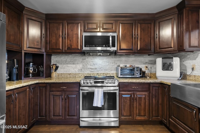 kitchen featuring appliances with stainless steel finishes, dark brown cabinets, and decorative backsplash