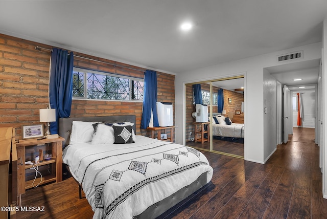 bedroom with brick wall, hardwood / wood-style floors, and a closet