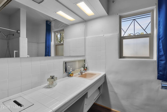 bathroom featuring vanity, a shower, a healthy amount of sunlight, and decorative backsplash