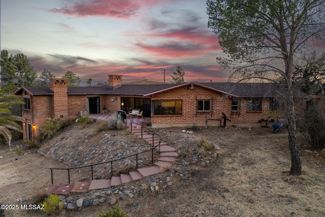 back house at dusk featuring a patio