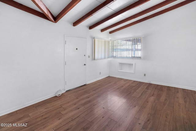 empty room featuring vaulted ceiling with beams and hardwood / wood-style floors