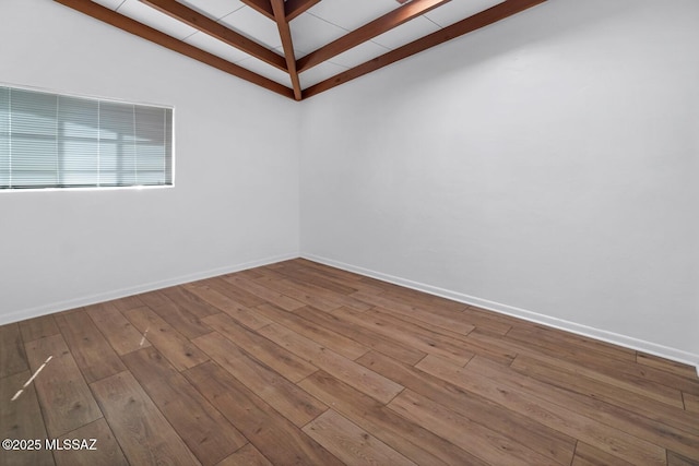 spare room featuring hardwood / wood-style flooring and vaulted ceiling with beams