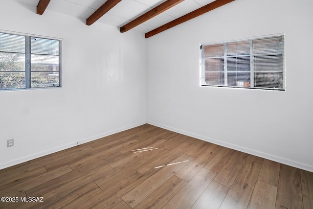 empty room with wood-type flooring and vaulted ceiling with beams