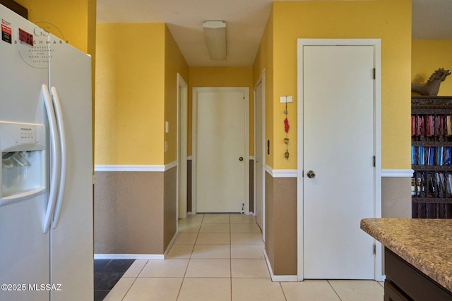 corridor featuring baseboards and light tile patterned flooring