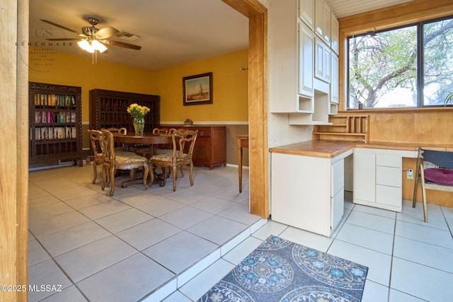 kitchen featuring visible vents, white cabinets, light tile patterned floors, ceiling fan, and built in study area