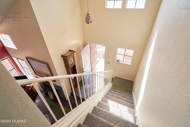 stairway featuring carpet flooring, baseboards, and a towering ceiling