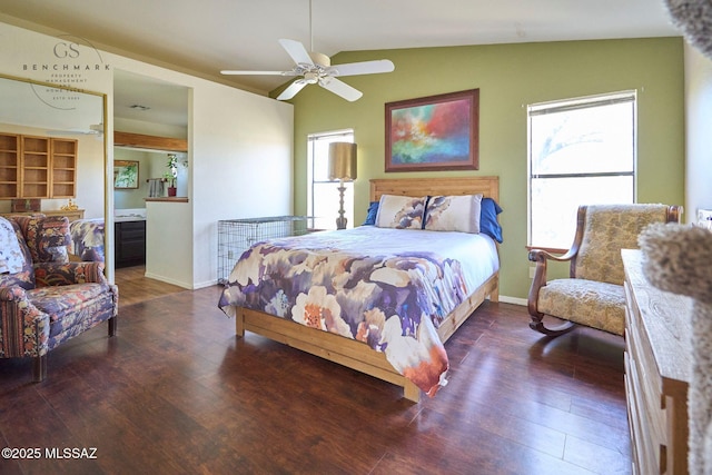 bedroom featuring wood finished floors, baseboards, lofted ceiling, ceiling fan, and ensuite bathroom