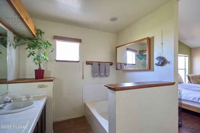 ensuite bathroom with ensuite bath, vanity, a garden tub, and wood finished floors