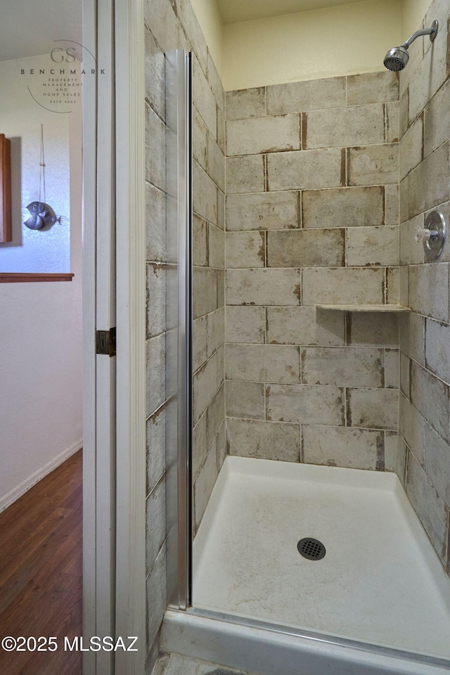 bathroom featuring wood finished floors and a shower stall