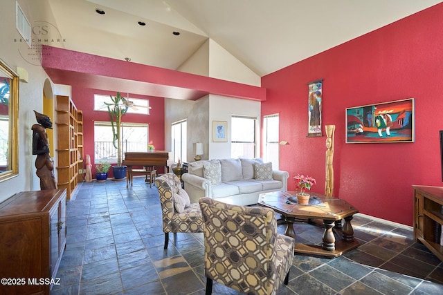 living room with high vaulted ceiling and stone tile floors