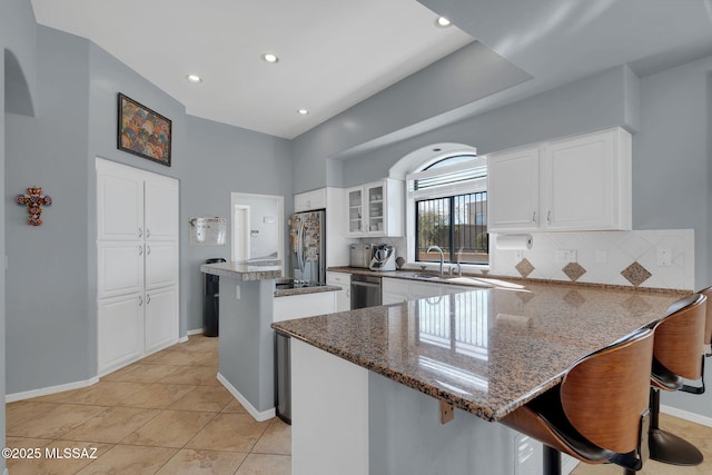 kitchen with appliances with stainless steel finishes, a center island, dark stone countertops, and white cabinets