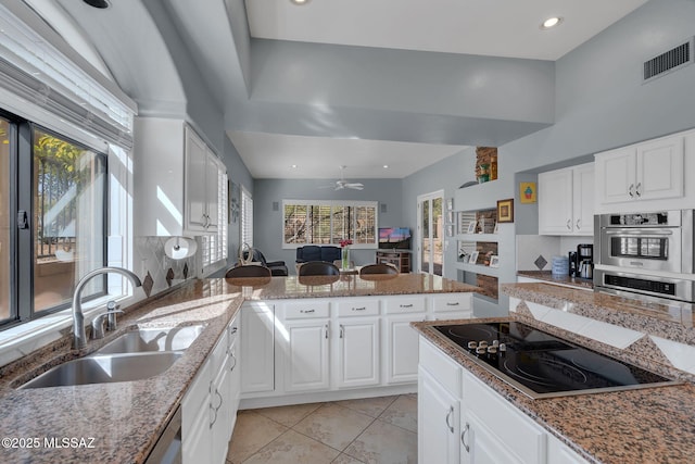 kitchen featuring sink, stone counters, white cabinetry, light tile patterned flooring, and black electric cooktop