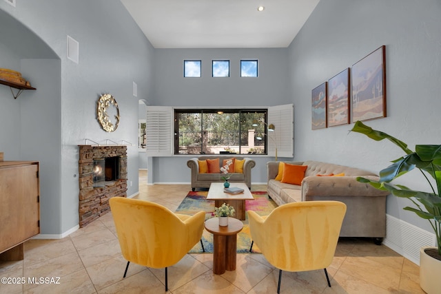 tiled living room with a towering ceiling and a fireplace