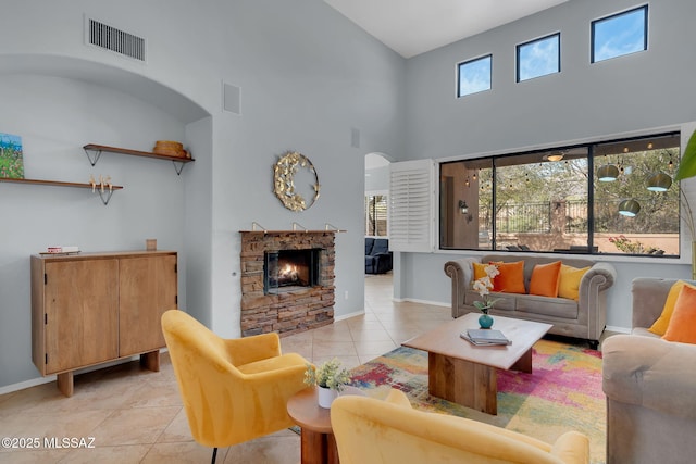 living room featuring light tile patterned flooring, a towering ceiling, plenty of natural light, and a fireplace