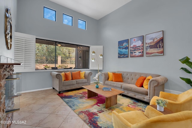 tiled living room with a stone fireplace and a towering ceiling