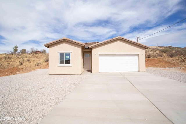 view of front of property with stucco siding, an attached garage, a tile roof, and driveway